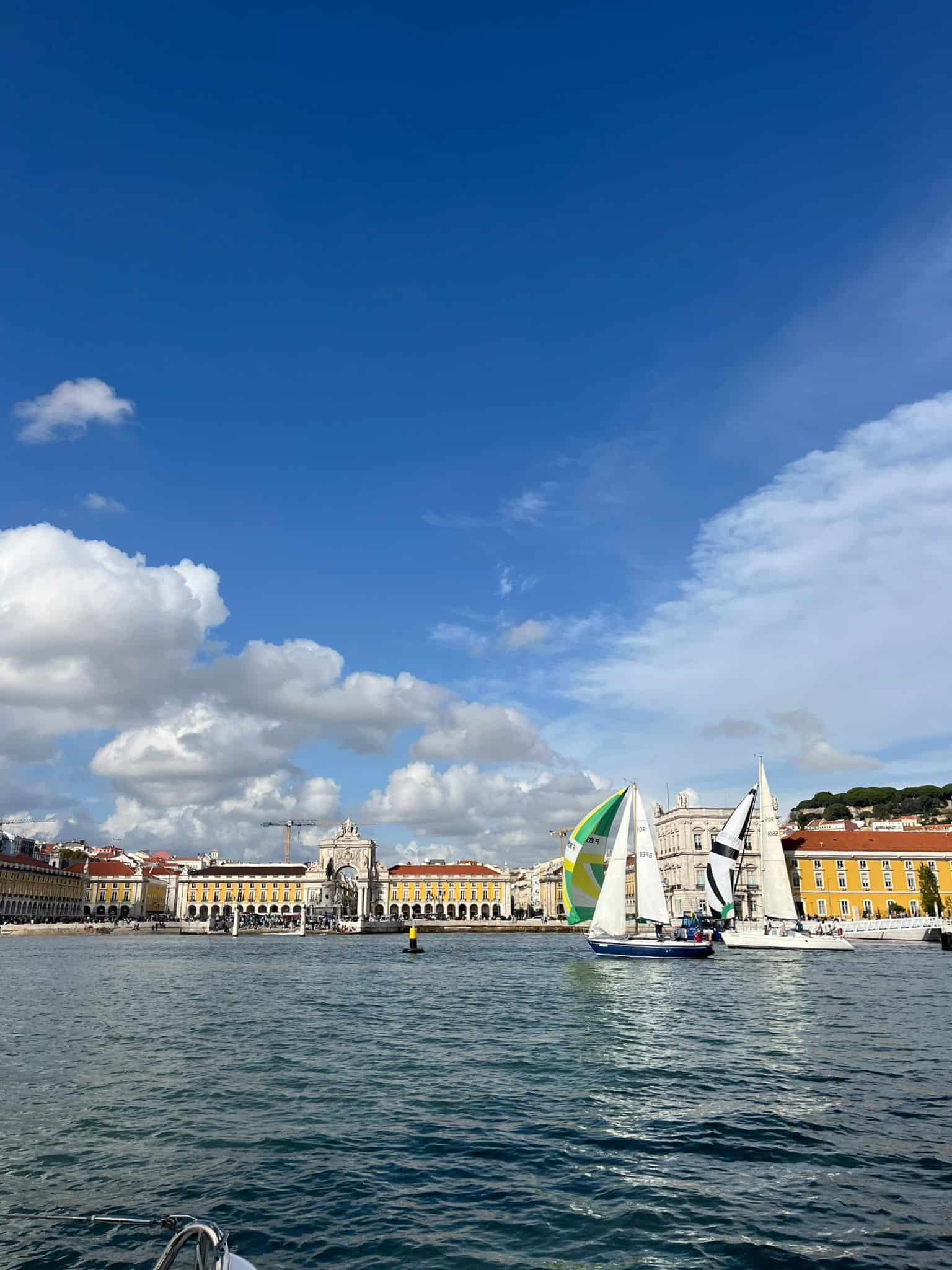 Sailboats passing Lisbon's waterfront on the Tagus